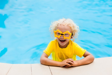 Naklejka premium Child with goggles in swimming pool. Kids swim.