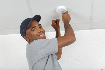 electrician removing battery from smoke detector