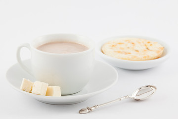 Cup of hot chocolate with cheese and arepa served in white dishware