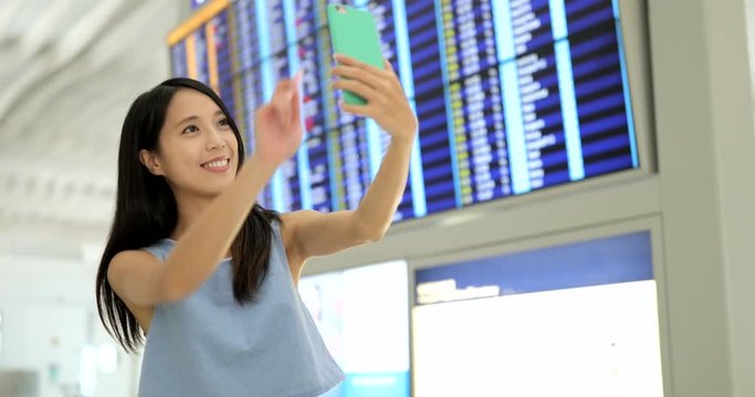 Woman taking selfie with cellphone at airport