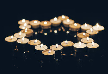 Burning candles in the shape of a star of david on a black background. Bokeh on dark backdrop, shallow depth of field