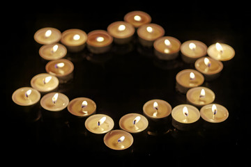 Burning candles in the shape of a star of david on a black background. Bokeh on dark backdrop, shallow depth of field