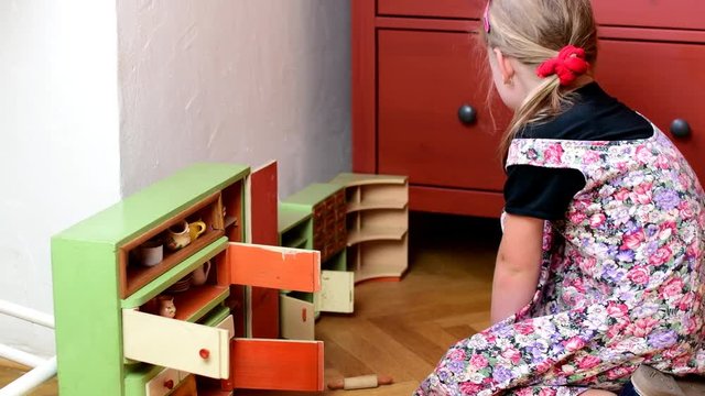 Cute little girl plays with vintage toys. Girl's body, girl wears flowered dress