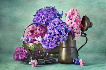 Beautiful hyacinth flowers in a copper pitcher on a textural background. 