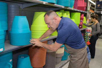 man tidying up colorful pots at a shope
