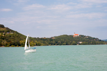 Tihany Peninsula with the Abbey and a sailboat viewed from a ship's deck