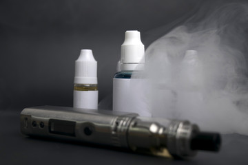 electronic cigarette, vape device next to  e liquid bottles and tools.