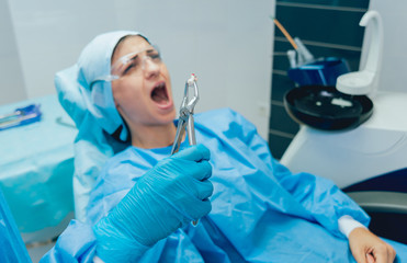 Dentist using surgical pliers to remove a decaying tooth. Modern dental clinic