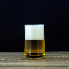 Glass beer on wooden table with black background