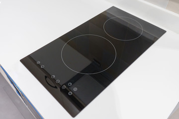 Modern black induction stove, cooker, hob or built in cooktop with ceramic top in white kitchen...