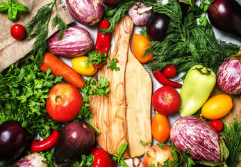 Cooking background, fresh vegetables and spicy herbs on a cutting board, top view
