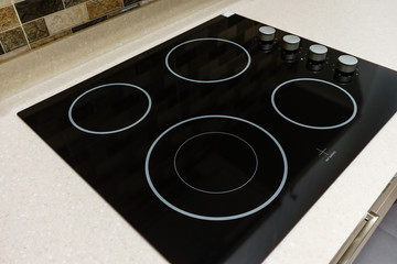 Modern black induction stove, cooker, hob or built in cooktop with ceramic top in white kitchen...