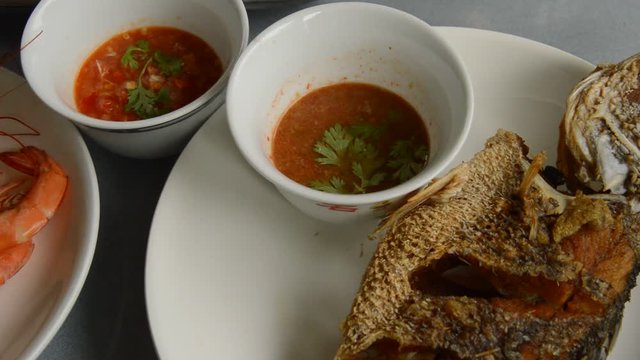 baked salt prawn panning to deep fried bass fish dipping spicy and sour sauce on table