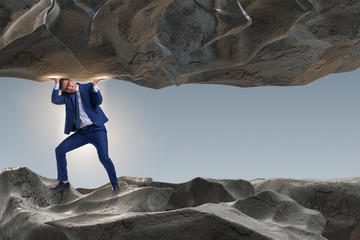 Businessman supporting stone under pressure