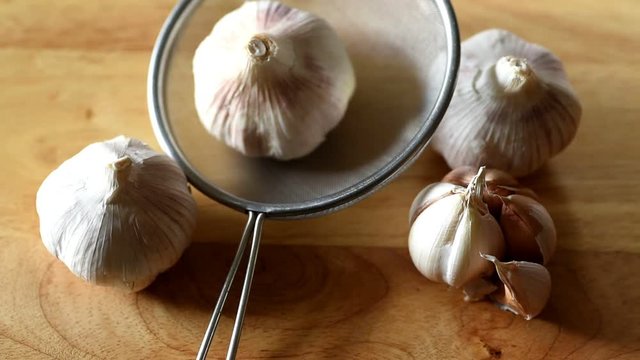 Close up of whole garlic on a brown wooden background there is a change of light and shadow.