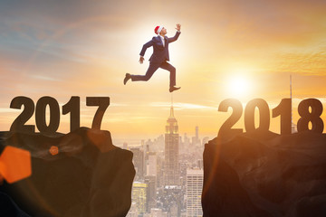 Fototapeta na wymiar Businessman in santa hat jumping from 2017 to 2018