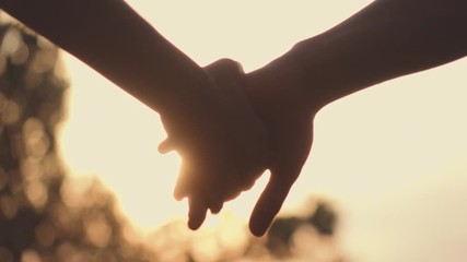 Close up of two Lovers Joining Hands. SLOW MOTION 240 fps. Detail Silhouette of Man and Woman holding hands over the Sunset Lake Background. Couple Trust, Love and Happiness concept. - Powered by Adobe