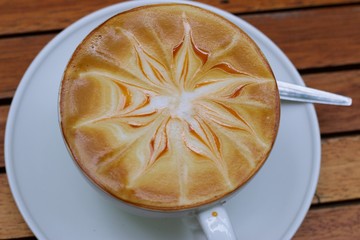Coffee arts is in white cup on wooden table