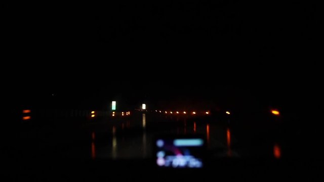 Car drive at night toll road at gps windshield POV rain or snow bad weather conditions. Approaching TELEPASS tollgate checkpoint lights with signs showing automatic ticket system machine in Italian
