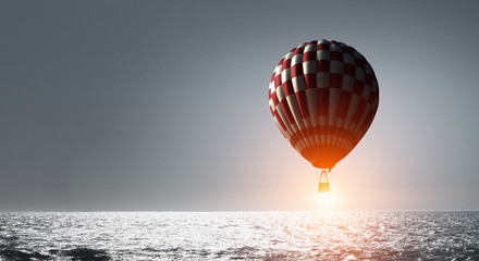 Aerostat floating in day sky. Mixed media
