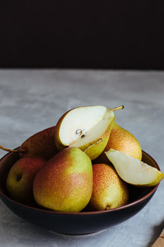 Ripe pears in a plate on a white stone background. Toned.
