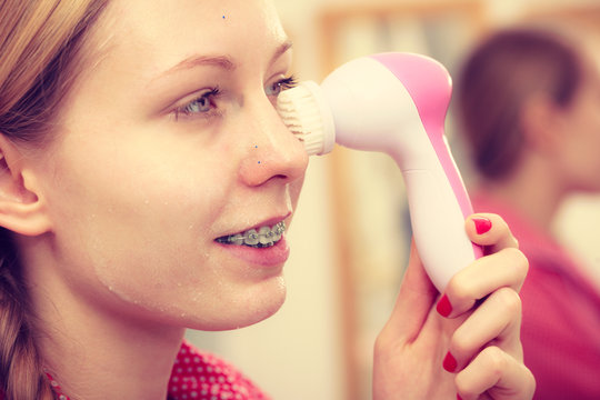 Woman Using Facial Cleansing Brush On Face