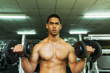 Fototapeta na wymiar Fitness man in training showing exercises with dumbbells in gym
