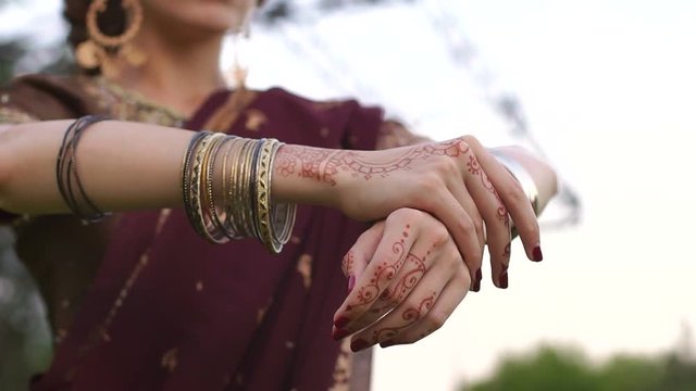Beautiful young Indian girl wearing a Sari with a tattoo on the hands in the Park outdoors. Close-up of the hands painted with mehendi.