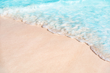 Beach background copy space of water wave tide over white sand texture. Turquoise ocean sea tropical travel vacation concept.