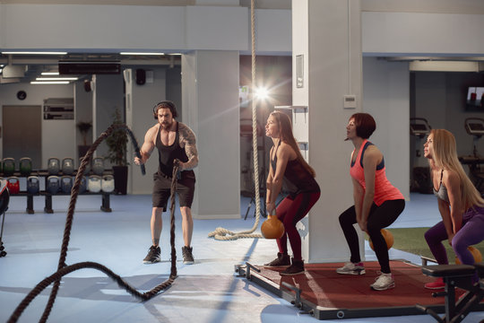 group of fitness people doing exercise with weights, rope, parallel bars in the gym