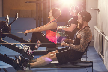 Mid section of people exercising on rowing machine at gym