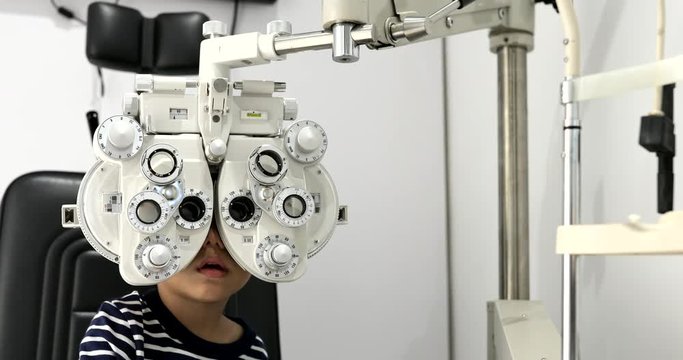 Little boy undergoing eye test with phoropter