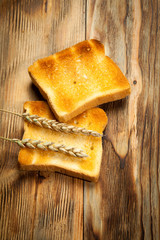Toasts of bread and wheat on an old wooden background
