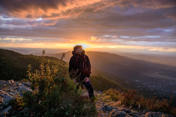 Amazing sunset on a mountain top - man with alpine equipment enjoying the breathtaking view under the stormy sky