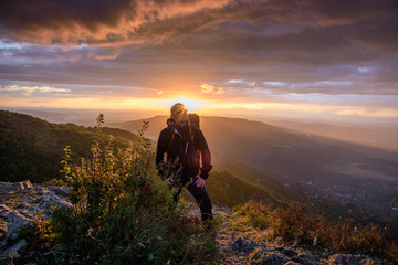 Amazing sunset on a mountain top - man with alpine equipment enjoying the breathtaking view under the stormy sky