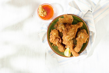 Fried chicken legs with red spicy sauce on wooden table