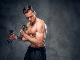 Shirtless male holds a set of dumbbells.