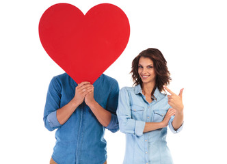 woman pointing finger to her lover holding heart over  face