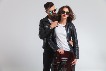 Naklejka premium rock and roll couple standing embraced and showing electric guitar