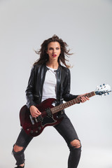 Fototapeta premium young woman in leather jacket playing electric guitar