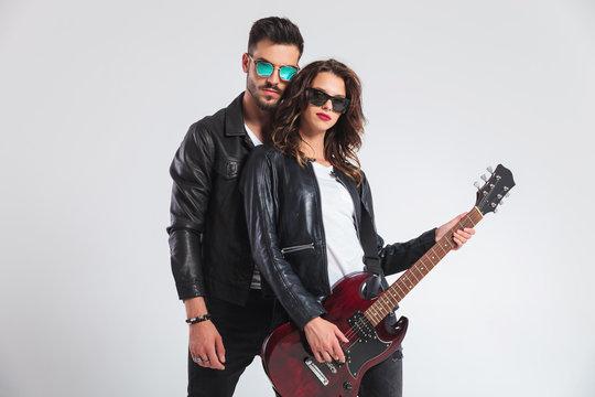 punk man behind his woman playing electric guitar