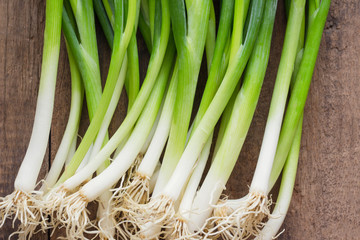 Fresh spring onion on rustic wood table.Close up scallions or spring onion on wood plank in top view flat lay. Prepare spring onion for cooking. Food and vegetable concept for background or wallpaper.