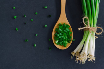 Fresh spring onion on black granite table. Close up on chopped scallions or spring onion in top...