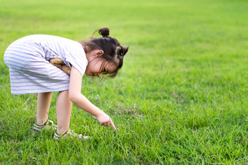 Cute girl find something in the green fields.Kid play with teddy bear toy.Selective focus with copy space.Health an education concept.