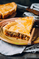 A pieces of Fresh Meat pie on the wooden board on table background. Pie with cabbage and minced beef
