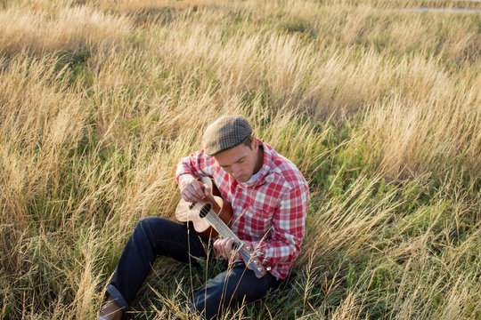 picture of young man ukulele player in the fields  