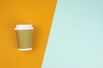 Flat lay of Take out paper coffee cup on blue and orange background. Copy space. Mock up.