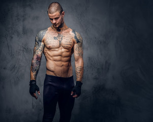 Fototapeta na wymiar Muscular, shirtless, tattooed male over grey background.
