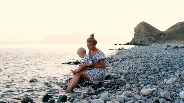 Evening, sea beach. The son sits on his mother's lap and eats fruit and berries