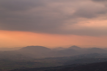 Beautiful dusk over some mountains with orange and red tones in the sky, clouds and hills